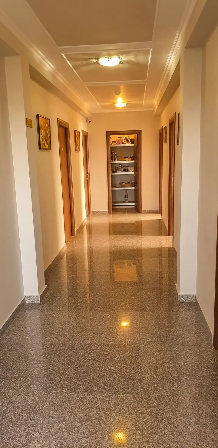Hol cu pardoseală lucioasă și uși din lemn, după editare, cu lumină caldă.